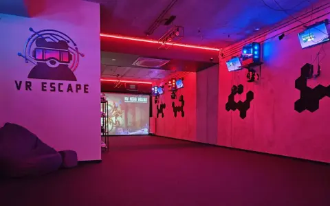 Częstochowa escape room z neonowym oświetleniem, logo VR ESCAPE i ekranem projekcyjnym.