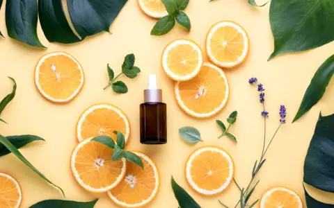 Siero viso con niacinamide e acido glicolico, circondato da fette d'arancia, foglie verdi e lavanda.