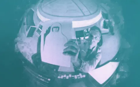 Inquadratura soggettiva: un astronauta in una navicella tiene in mano un disegno di sé stesso con casco.