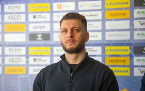 Aleks Vlah, z charakterystyczną brodą i krótką fryzurą, pozuje na tle ścianki z logotypami sponsorów, m.in. "ECHO" i "realme".