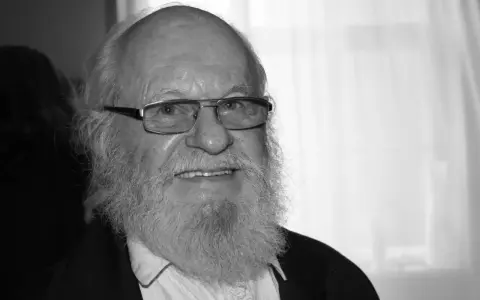 Uśmiechnięty Aleksander Skowroński z siwą brodą i okularami.