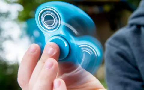 En blå finger spinner snurrar snabbt i handen, med suddiga kanter som visar rörelsen.