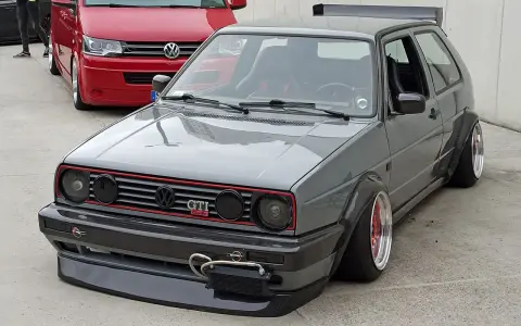 Szary, zmodyfikowany Volkswagen Golf GTI z szerokimi błotnikami i spojlerem.