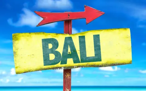 Strzałka kierunkowa wskazuje drogę do Bali. W tle błękitne niebo i morze.