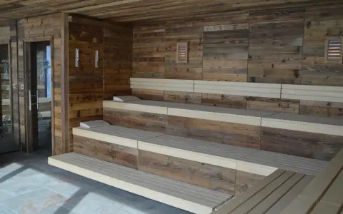 Drewniana sauna w domu z wielopoziomowymi ławami i kamienną podłogą. Idealne miejsce na relaks.