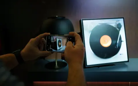 Ręce trzymają smartfon, fotografując gramofon. Odkryj gadżety do domu, o których nie miałeś pojęcia, jak ten nowoczesny sposób na docenienie klasycznej muzyki.