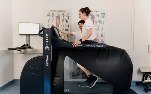 Donna in gravidanza usa un tapis roulant anti-gravità con un fisioterapista.