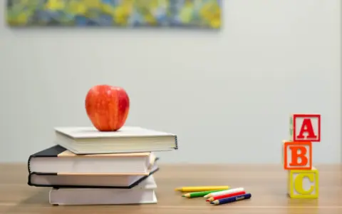 Stos książek, jabłko, kredki i kostki z literami ABC. Nauka idzie szybko, gdy mamy wszystko pod ręką.