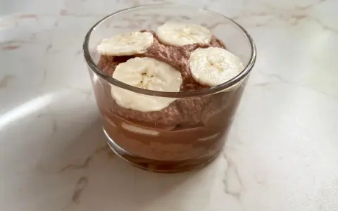 Schokoladiger Genuss: Ein Glas mit luftiger Nutella-Creme mit Mascarpone, garniert mit frischen Bananenscheiben.