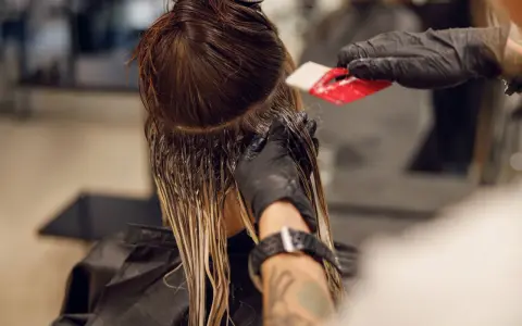 Friseur trägt Farbe auf, um einen sanften Farbverlauf zu erzielen. Die color melting Technik lässt die Töne harmonisch ineinander übergehen.
