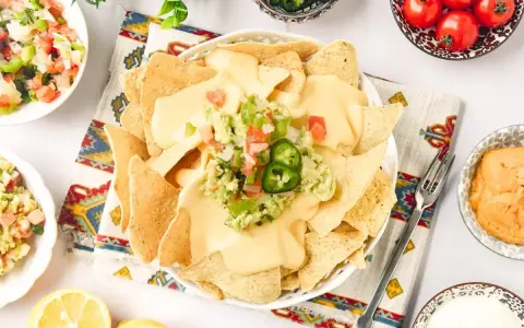 Nachos con queso cubiertos de guacamole y pico de gallo, listos para disfrutar.
