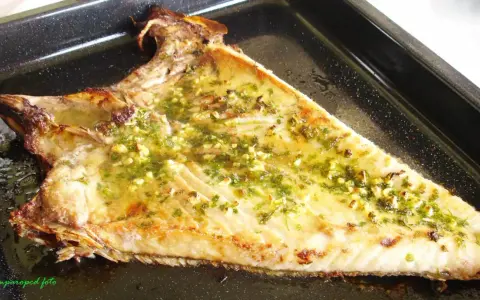 Deliciosa ventresca al horno, dorada y jugosa, con un aderezo de ajo y perejil que invita a probarla.