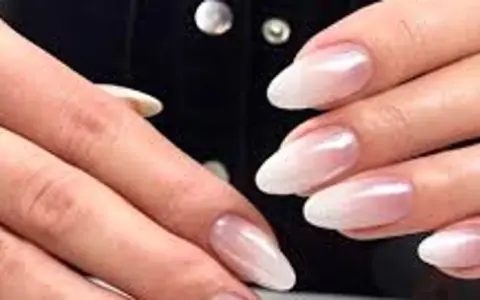 Dłonie z paznokciami w stylu french z pyłkiem, delikatny ombre od różu do bieli, subtelny blask.