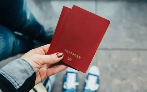 Dłoń trzyma paszport. Zastanawiasz się, ile kosztuje zmiana nazwiska? Czas na podróż i nowe życie!