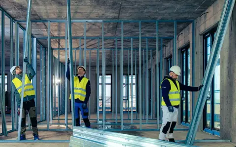 Budowlańcy montują konstrukcję ścian z profili UA. Praca na budowie postępuje.