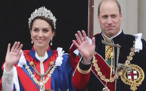 Kate Middleton och Prins William, medlemmar av brittiska kungahuset, vinkar från en balkong i sina högtidliga dräkter och juveler.