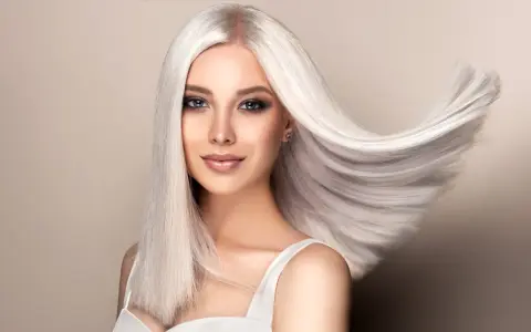 Kobieta z olśniewającymi, długimi włosami w odcieniu perłowy blond, które falują na wietrze.