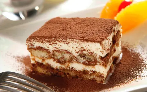 Pyszne tiramisu Ani Starmach, posypane kakao, z owocami i wisienką. Idealne na deser.