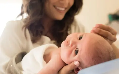 Lächelnde Mutter hält ihr Baby, das gerade einen Wachstumsschub durchmacht.
