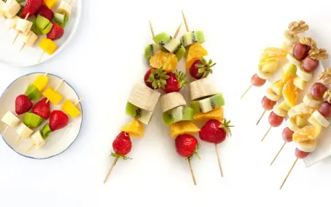 Brochetas de frutas coloridas con fresas, kiwi, plátano, mango, naranja, uvas y nueces. ¡Un postre refrescante y saludable!