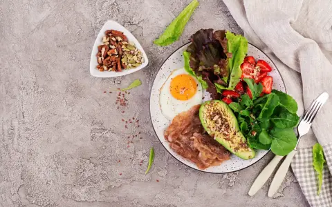 Śniadanie keto: jajko sadzone, bekon, awokado, sałatka z truskawkami i orzechy. Idealne na początek dieta ketogeniczna.