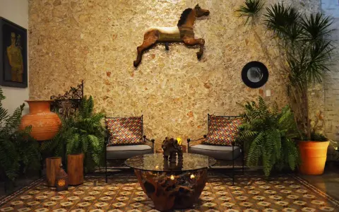 Un caballo decorativo adorna la pared de un patio exterior, complementado por plantas exuberantes y un rincón acogedor.