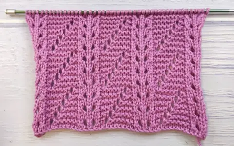 Muestra de tejido con puntos fantasía crochet en color rosa, con un patrón de hojas caladas.