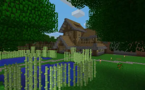 Drewniany dom z kamiennymi elementami, otoczony bambusami i wodą. W Minecraft można budować takie cuda i tworzyć własne światy.