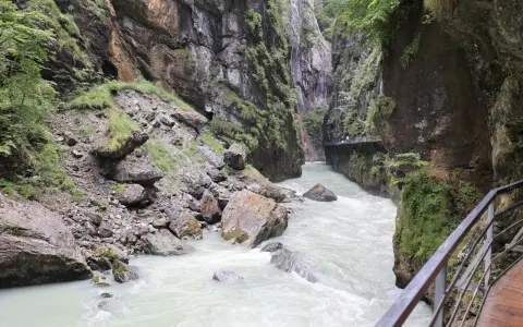 Aare Gorge, with its powerful river and dramatic cliffs, leads towards the Reichenbach Falls. A wooden walkway hugs the canyon wall.