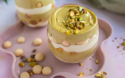 Pyszny deser w pucharku: krem pistacjowy z mascarpone, przełożony biszkoptami i posypany pistacjami.