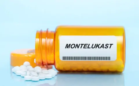 Pomarańczowa butelka leku MONTELUKAST, z której wysypały się białe tabletki.