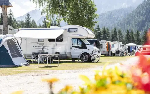 Kampery i namioty na malowniczym kempingu Rocchetta, otoczone górami i lasem.
