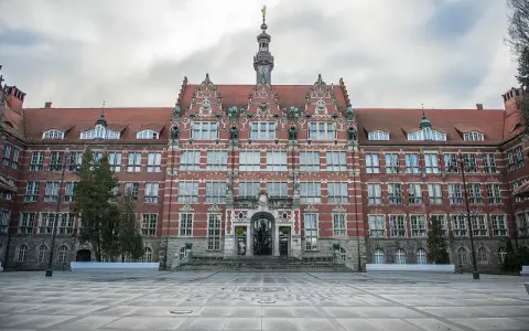 Imponujący budynek Politechniki Gdańskiej, jednej z ważnych uczelni Gdańsk, z charakterystyczną wieżą zegarową i ozdobną fasadą.