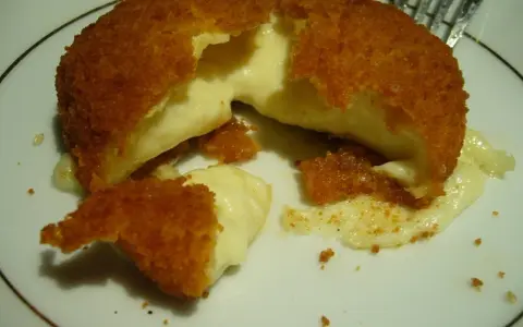 Pyszny camembert w panierce, z którego wypływa gorący, ciągnący się ser. Idealna przekąska na ciepło.