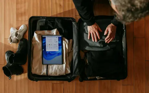 Pakowanie lot bagaż: tablet z systemem Windows, ubrania, buty i akcesoria.