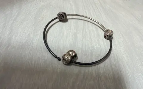 Srebrna bransoletka Pandora z charmsami, która z czasem może żółknąć z powodu reakcji chemicznych.