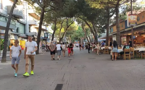 Passeggiata serale nel riccione centro storico, tra negozi e ristoranti all'aperto sotto gli alberi.