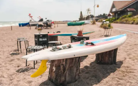 Windsurfbrett am Strand, ein echter Dahme Geheimtipp für Wassersportler. Gelbe Finne ragt aus dem Sand.