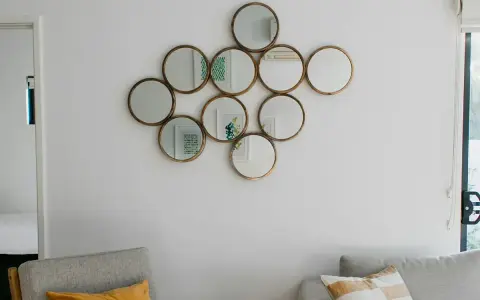Un conjunto de espejos redondos dorados, dispuestos como una constelación, es una excelente idea de qué poner en una pared vacía.