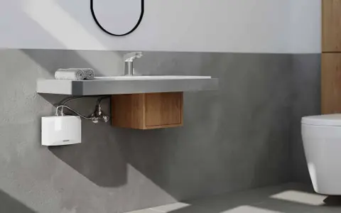 Moderner **Durchlauferhitzer** unter dem Waschbecken im **Bad**. Neben dem WC und dem Waschbecken mit Holzelement.