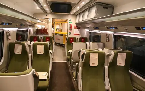 Wnętrze wagonu PKP Intercity. Puste zielone fotele czekają na pasażerów. Pamiętaj, że pkp intercity bilet bez gwarancji miejsca do siedzenia może oznaczać podróż na stojąco.
