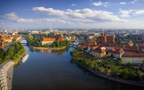 Majówka we Wrocławiu: malowniczy widok na Ostrów Tumski z rzeką i zabytkowymi budynkami.