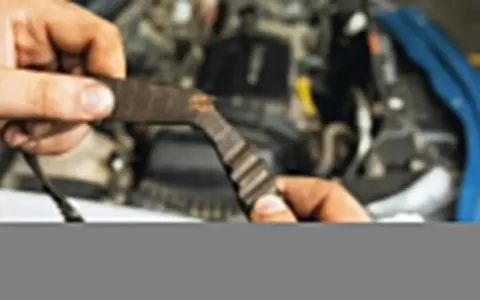 Zużyty pasek rozrządu w dłoni mechanika. Wymiana rozrządu jest kluczowa dla sprawnego działania silnika.