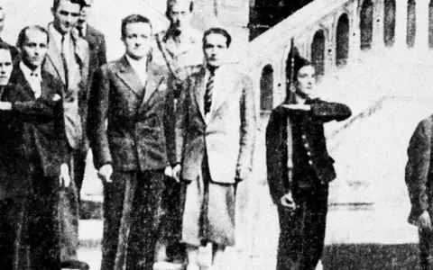 Groupe d'hommes en costume, dont Henri Frenay et François Mitterrand, posant devant un escalier.