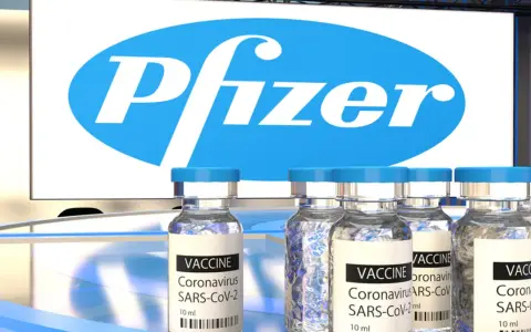 Szczepionki Pfizer na COVID-19 w ampułkach, z logo firmy w tle.