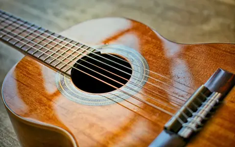 Klasyczna gitara, gotowa do wykonania znanych utworów na gitarę klasyczną. Jej drewniane, lśniące pudło rezonansowe zaprasza do muzycznej podróży.