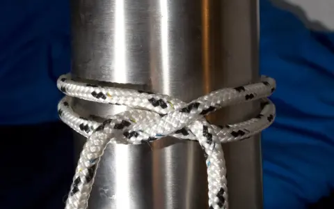 Un nœud pare battage, simple et efficace, sécurise une corde blanche et noire autour d'un mât métallique.