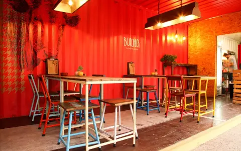 Decoración de restaurante con paredes rojas, mural de vaca y mesas coloridas.