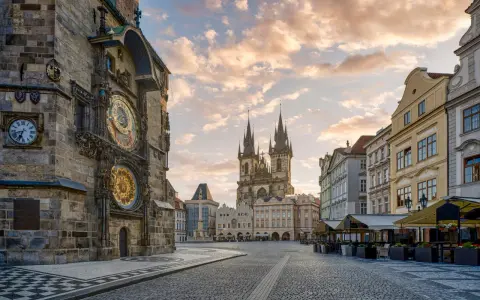 Praga co zobaczyć w jeden dzień: Ratusz Staromiejski z zegarem astronomicznym i Kościół Marii Panny przed wieżami w blasku porannego słońca.