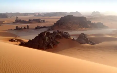 Sanddünen und Felsformationen in der algerischen Kulturlandschaft der Sahara. Ein Ort, der Geschichten von Nomaden und alten Zivilisationen erzählt.